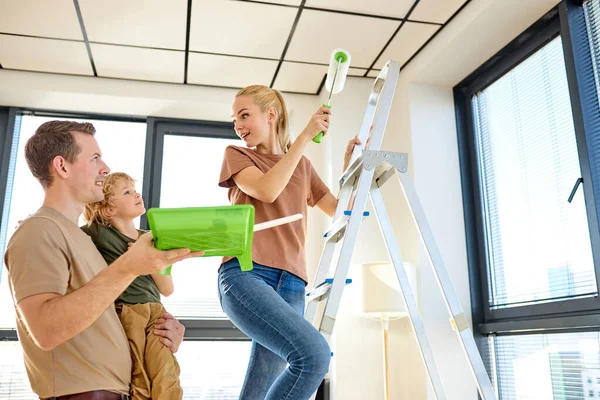 Repair in apartment. Nice mother pain the ceiling, husband and son help her — Fotografia de Stock