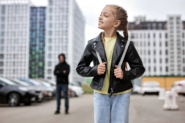 Portrait d'une enfant heureuse et souriante marchant seule dans la rue, tandis que terrible maniaque la regardant — Photo