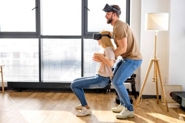 Kadın ve erkeğin yan görüşü. VR gözlükleriyle eğleniyorlar. Oynamayı öğreniyorlar.