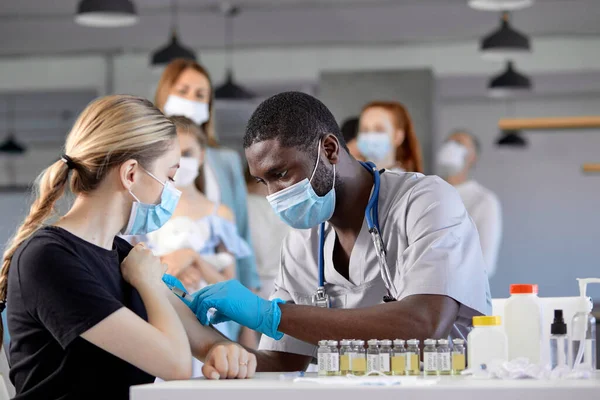 Black afro male Doctor vaccinating cute female,side view. People vaccination concept — Fotografia de Stock