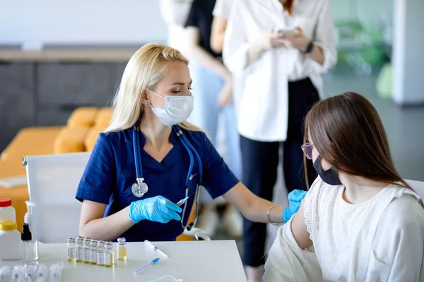 Kvinnlig patient blir skjuten på sjukhus eller klinik. Yrkesmässig kaukasisk läkare i arbete — Stockfoto