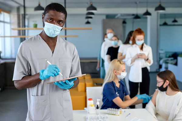 Tehlikeli viral hastalıklara karşı aşı yapılırken elinde tabletle kendinden emin bir erkek doktor. — Stok fotoğraf