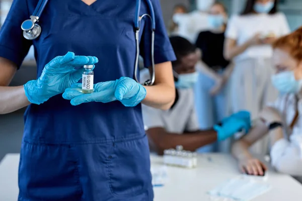 Cropped female doctor or scientist with vaccine bottle in hospital during mass vaccination — Stock Fotó