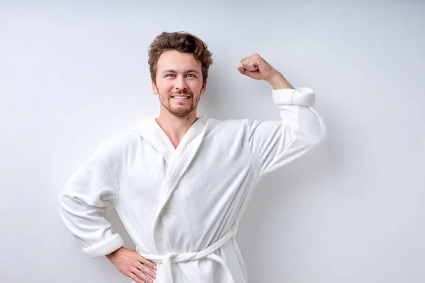 Jonge man met baard toont spieren na het beoefenen van bodybuilding, in badjas — Stockfoto