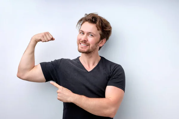 Look at my muscles. Strong powerful young man raises arms and shows biceps — Fotografia de Stock