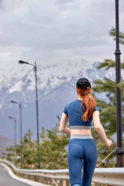 Οπίσθια άποψη για Redhead Sporty Γυναίκα Jogging Μεταξύ των βουνών, Απολαύστε προπόνηση — Φωτογραφία Αρχείου