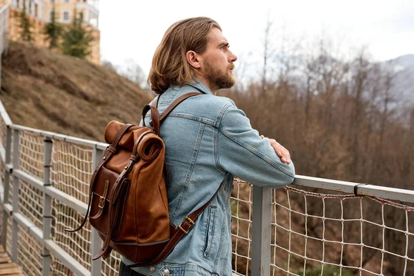 Joven hombre caucásico explorando la naturaleza en el campo, caminando a través del puente — Foto de Stock