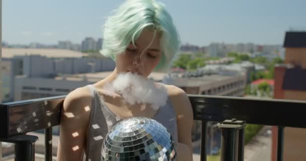 Dreamy woman with short green hair smoking electronic vapour cigarette on balcony — Stock Video