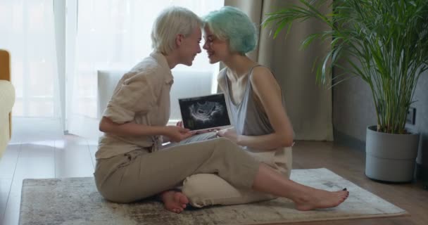 Молодая лесбийская пара отдыхает на полу, взволнована беременностью. Любовь, беременность, — стоковое видео