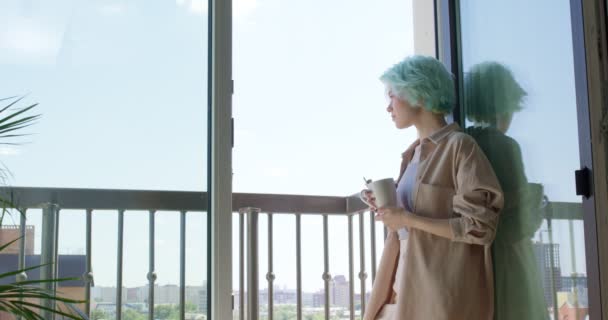 Feminino de cabelos curtos em desgaste casual de pé perto da janela, enquanto sua namorada veio com café da manhã — Vídeo de Stock