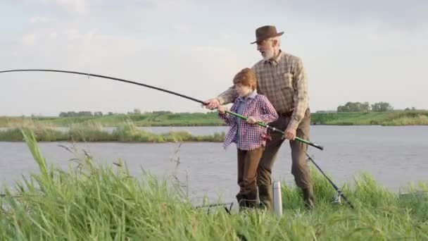 Fiske efter gädda, abborre, karp. Erfarna fiskare och barn pojke med spö, snurrande rulle — Stockvideo