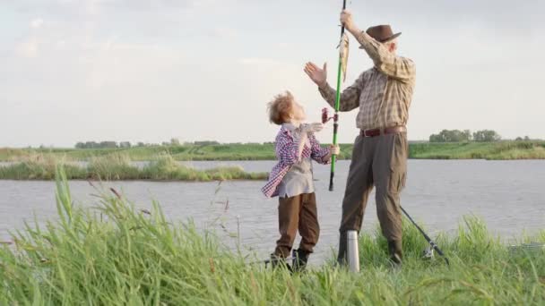 Pêche en famille. Enfant avec grand-père attraper le poisson, sur la rivière d'été dans la soirée — Video