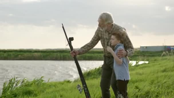 Şirin küçük çocuk ve büyükbaba gölde veya nehirde balık tutuyorlar, balık tutmayı öğreniyorlar. — Stok video