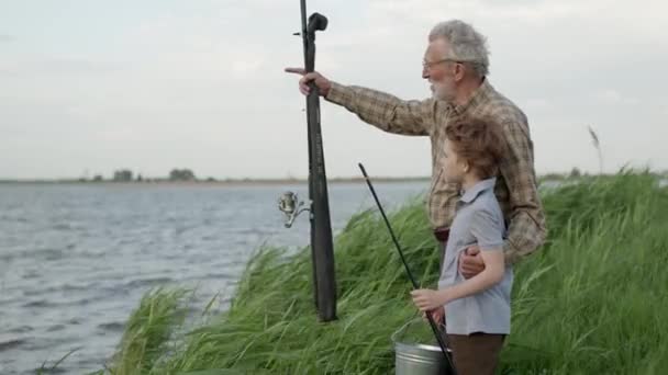 귀여운 소년 과 할아버지는 호수 나강에서 고기잡이를 하면서 고기잡이를 배우고 있다 — 비디오