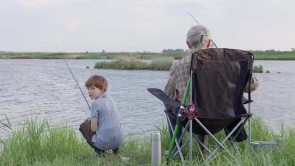 Petit-fils et grand-père ensemble poissons du champ près du lac. Le concept de famille — Video