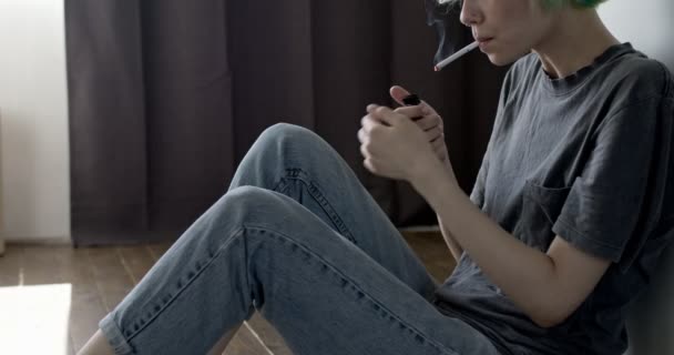 Deprimerad ung kvinna sitter på golvet hemma, röker cigarett, upprörd och desperat — Stockvideo