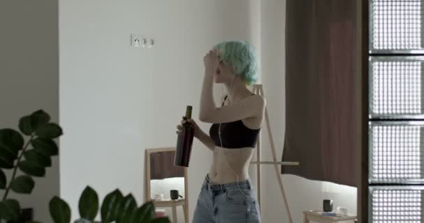 Depressieve en wanhopige vrouw die wijn drinkt en danst, in een koptelefoon, alleen — Stockvideo