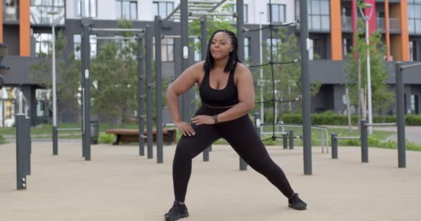Afrykańska gruba kobieta rozciągająca ciało, rozgrzewające mięśnie przed bieganiem lub treningiem — Wideo stockowe