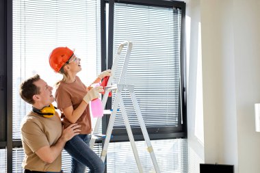 Gülümseyen bir çift yeni bir dairede birlikte ev tadilatı yapıyor, merdiven kullanıyor.