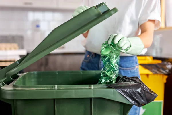 Молода біла жінка сортує пластикові пляшки в сміттєву банку, рятує планету, екологічно чисту людину — стокове фото
