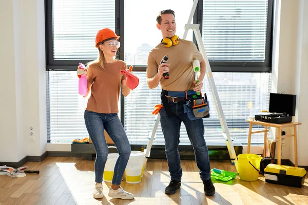 Feliz joven pareja sosteniendo herramientas y bailando durante la reparación de la casa —  Fotos de Stock
