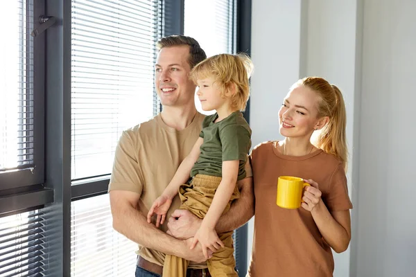 Hermosa familia con niño niño descansar en casa nueva, beber café, sonreír — Foto de Stock