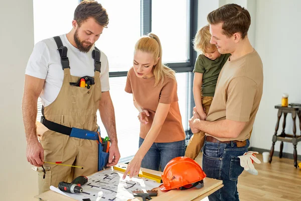 Família branca bonita com menino na reunião com o construtor do reparador, discutindo — Fotografia de Stock