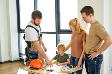 Üniformalı iyi bir müteahhit müşterilere yeni evin tamir planını açıklar.