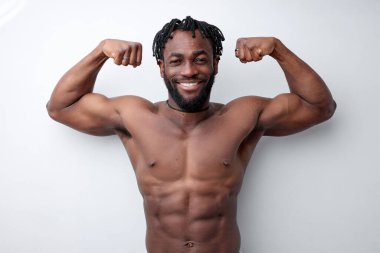 Beyaz stüdyo arka planında izole edilmiş, pazı gösteren Afro formda genç bir sporcu.