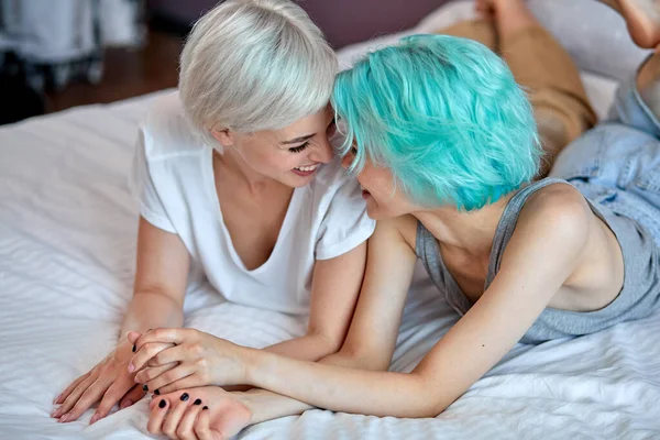 Positivo optimista amante del mismo sexo pareja femenina han descansado en la cama, riendo —  Fotos de Stock