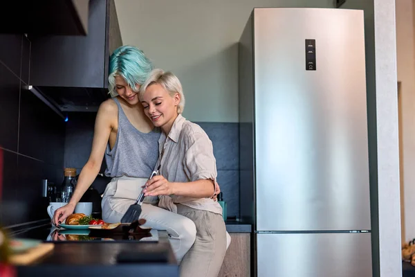 Boldog leszbikus lgbtq pár szerelmes ölelés, nevetés, miközben főzés a konyhában otthon — Stock Fotó