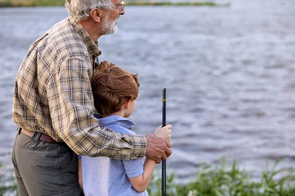 Barnbarn och farfar fiskar tillsammans på sjön. Begreppet familj, sommarsemester — Stockfoto