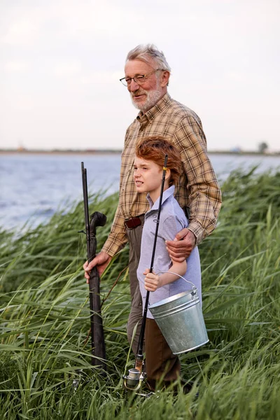 Fim de semana. Pescador sênior com menino usando vara de pesca com mosca no rio. Retrato de visão lateral — Fotografia de Stock