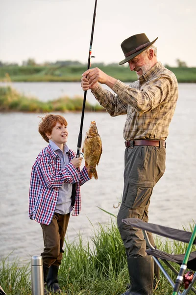 Atrapar el día. Feliz abuelo y niño pescando mientras que en la orilla del estanque — Foto de Stock
