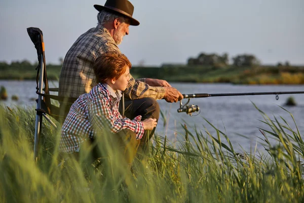A pesca de lúcio, poleiro, carpa. Pescador sênior experiente e criança com vara, pesca — Fotografia de Stock