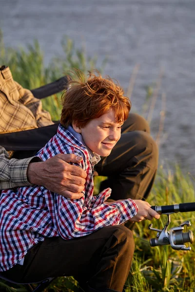 Gammal man och liten pojke tillsammans vid dammen. Liten pojke med fiskespö — Stockfoto