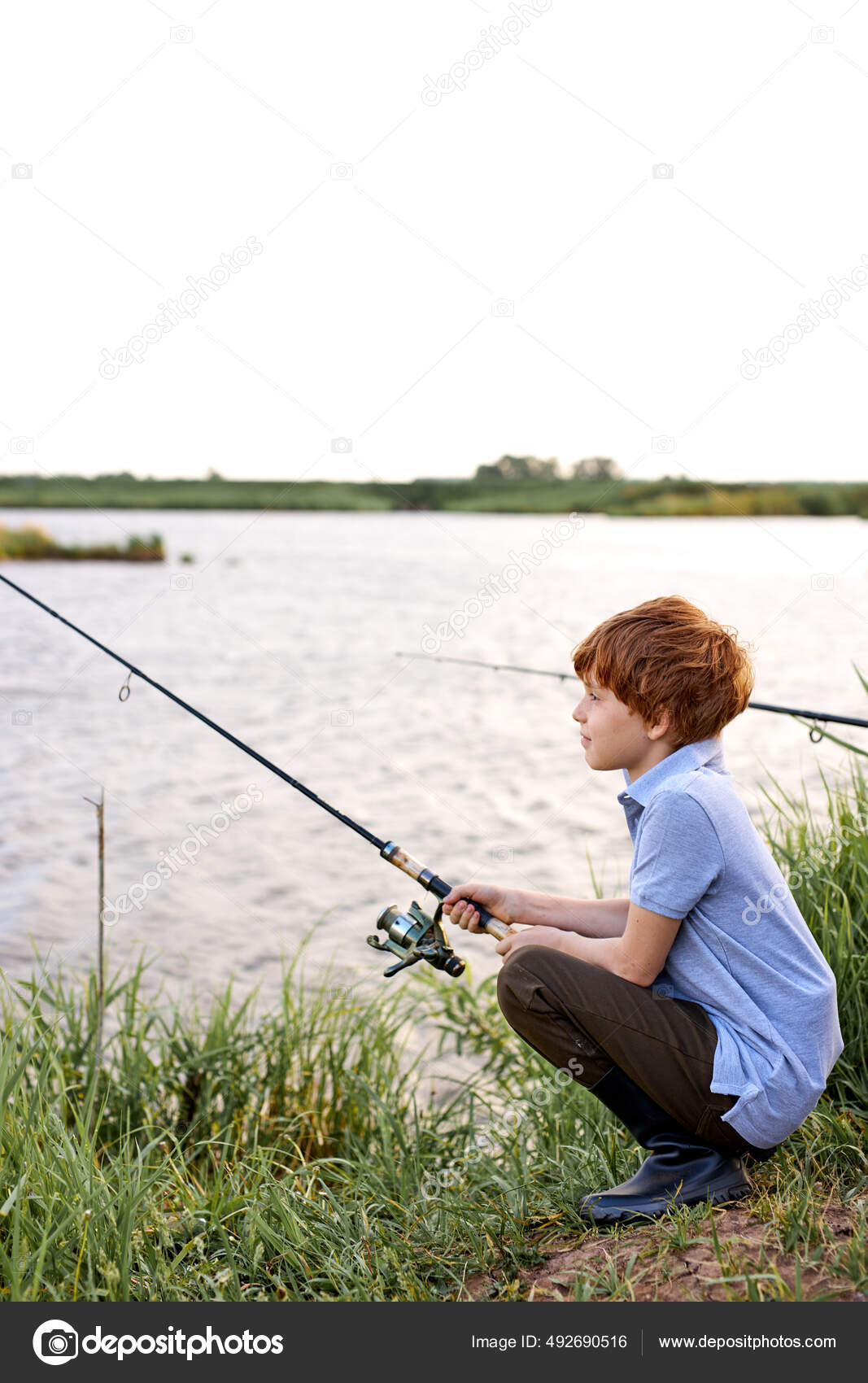 Little boy boy in rustic clothes sits with fishing rod in hands