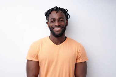 Beyaz arka planda izole edilmiş dişleriyle gülümseyen sıradan giyinmiş genç melez bir adam.