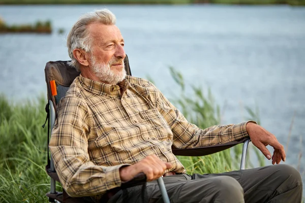 穿着格子衬衫的快乐老人在大自然的椅子上坐着休息 — 图库照片
