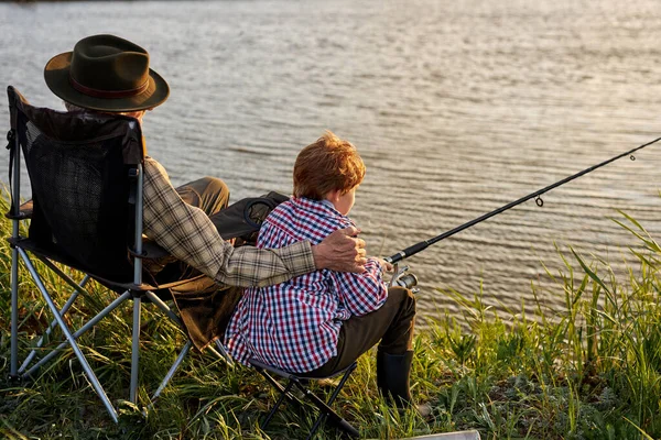 Bakifrån på farfar och sonson kastar fiske redskap i naturlig miljö — Stockfoto