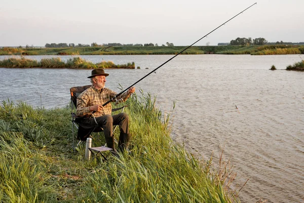 Ritratto di uomo anziano in vacanza in campeggio con canna da pesca, da solo all'aperto nella natura — Foto Stock