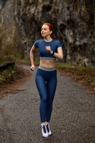 屋外で走る。レッドヘッドランナーの女性は春の森の中でジョギング。フィットネススポーツモデルジョギング — ストック写真