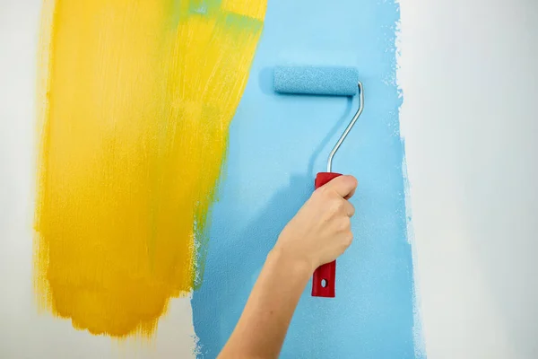Маленький хлопчик малює стіну з валиком. Колір фарби світло-блакитний і жовтий. Кімната вдома — стокове фото