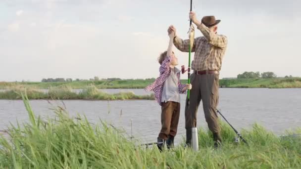 Чоловік сімейна риболовля. Кід з дідом ловить рибу, на літній річці ввечері — стокове відео