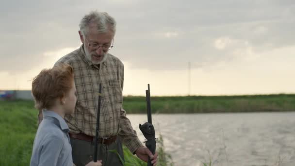 Büyükbabasıyla birlikte çocuk nehir kenarında balık tutuyor. Balıkçılık — Stok video