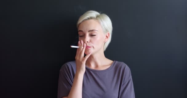 Relaxed Caucasian Female In Casual T-shirt Smoking Cigarette Isolated On Black — Stock Video