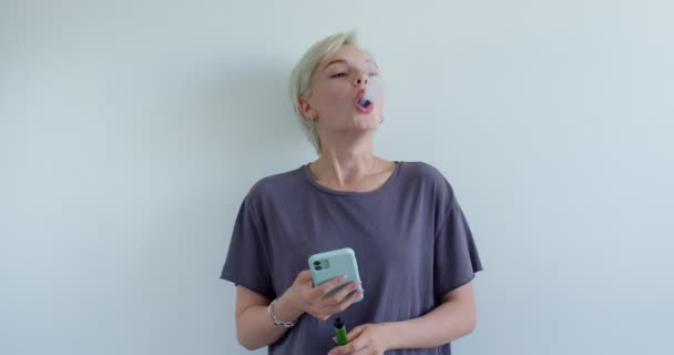 Vacker kvinna njuta av rökning elektronisk cigarett poserar isolerad över vit — Stockvideo