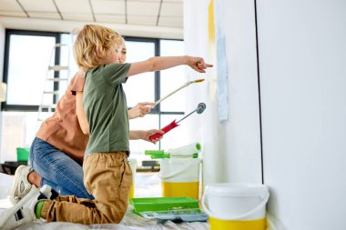 Hoş bir anne ve oğlu ev duvarlarını boyuyor ve eğleniyor, apartman dairesinde tamirat yapıyor.