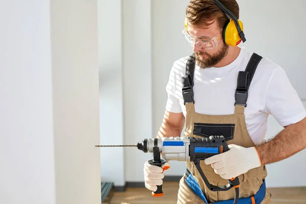 Homem caucasiano uso broca elétrica na parede em casa nova, espaço de cópia, melhoria Home — Fotografia de Stock