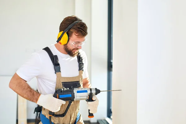 Zelfverzekerde blanke man met behulp van elektrische boor maken gat op de muur, versieren — Stockfoto